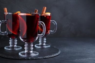 Photo of Aromatic mulled wine on black table, space for text