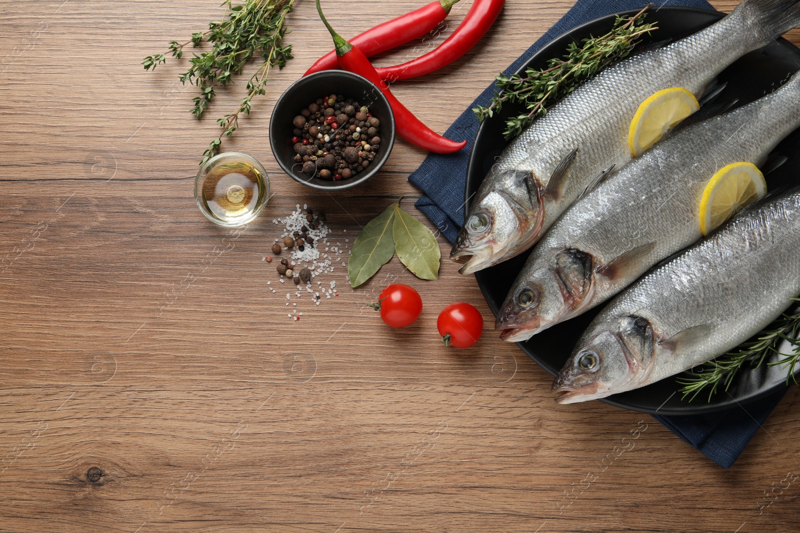 Photo of Tasty sea bass fish on wooden table, flat lay. Space for text