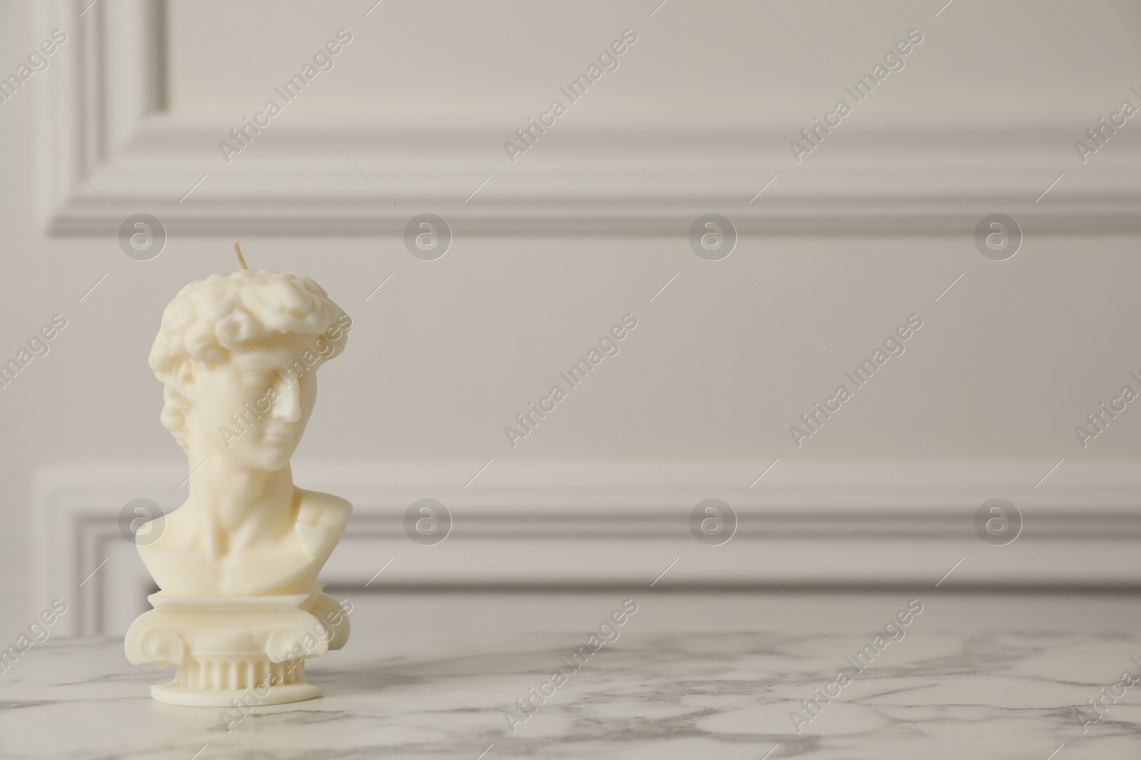 Photo of Stylish David bust candle on white marble table. Space for text