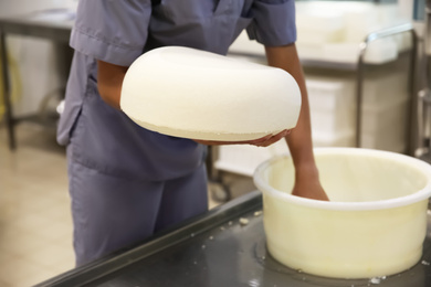 Photo of Worker holding fresh cheese at modern factory, closeup
