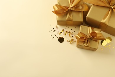 Photo of Beautifully wrapped gift boxes and confetti on beige background, flat lay. Space for text