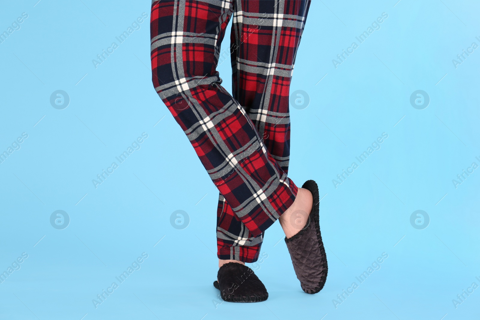 Photo of Man in warm soft slippers on light blue background, closeup