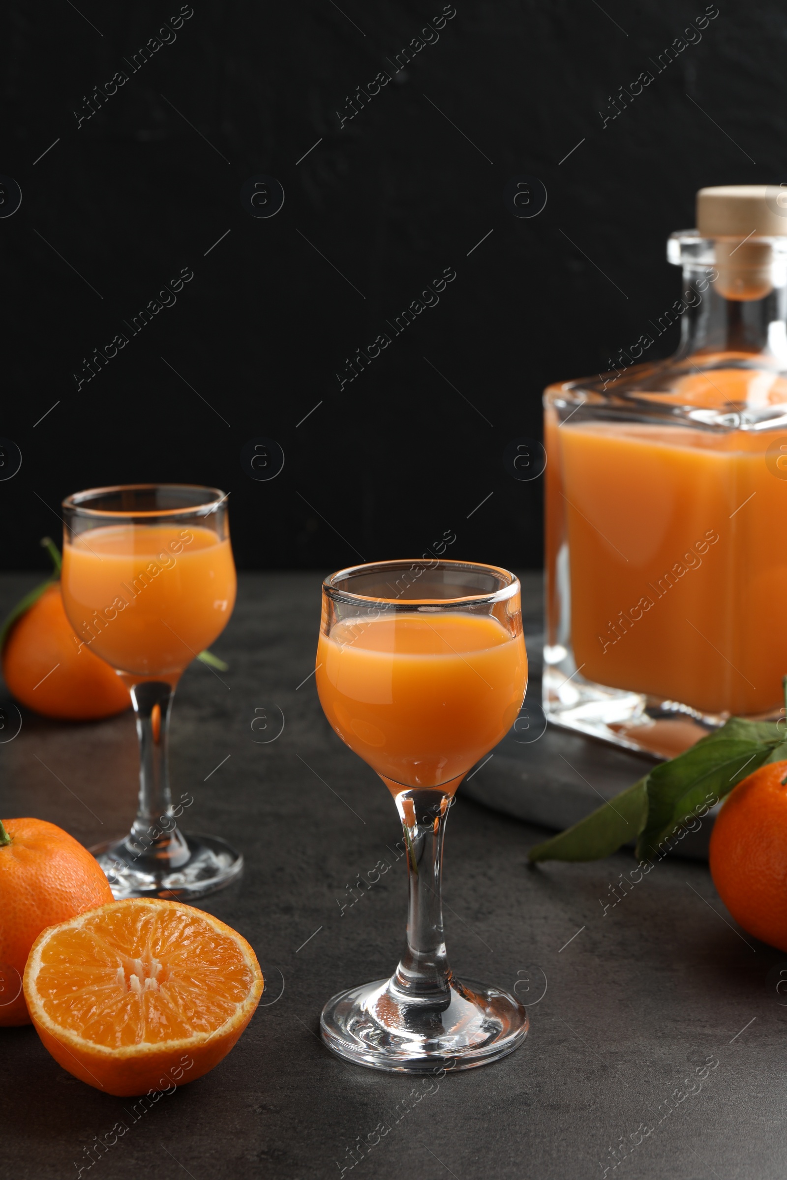 Photo of Delicious tangerine liqueur and fresh fruits on grey table