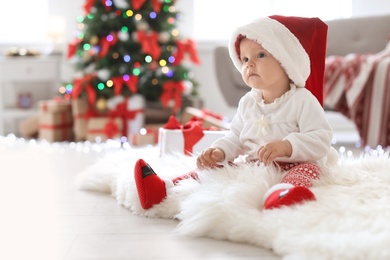 Cute baby in Santa hat on floor at home. Christmas celebration