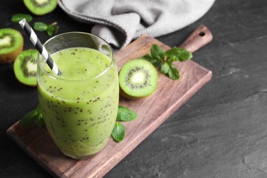 Photo of Delicious kiwi smoothie and fresh ingredients on black table, space for text