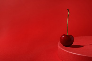 Photo of Sweet ripe cherry on red table, space for text