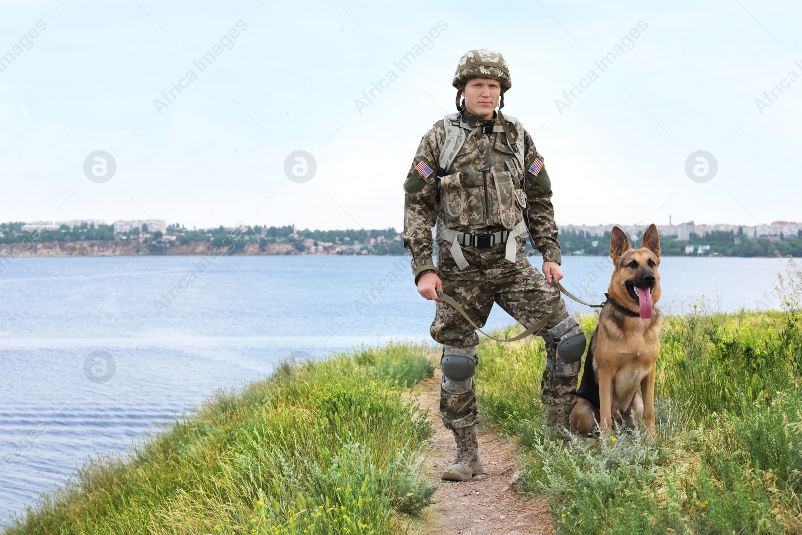 Photo of Man in military uniform with German shepherd dog near river