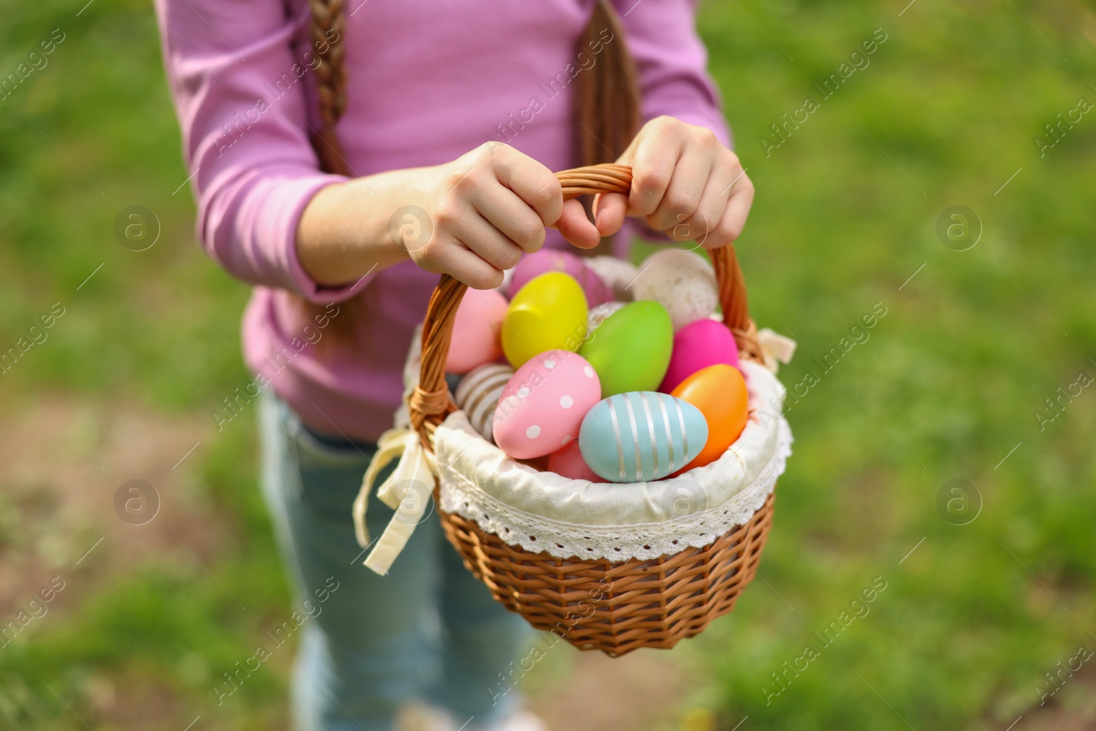 Photo of Easter celebration. Little girl holding basket with painted eggs outdoors, closeup