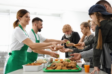 Photo of Poor people receiving food from volunteers indoors