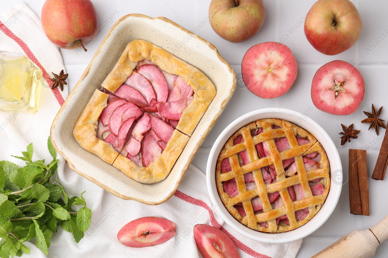 Photo of Delicious apple pie, galette and ingredients on white tiled table, flat lay