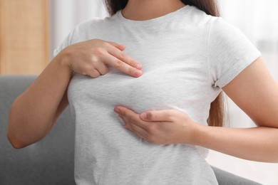 Photo of Woman doing breast self-examination at home, closeup