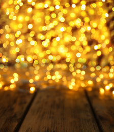 Blurred view of gold lights and wooden table, bokeh effect