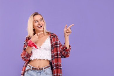 Photo of Portrait of happy hippie woman pointing at something on purple background. Space for text