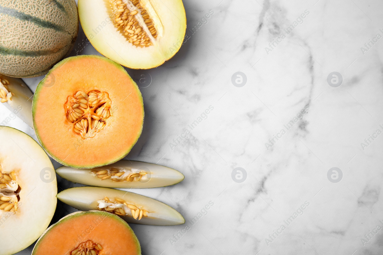 Photo of Tasty colorful ripe melons on white marble table, flat lay. Space for text