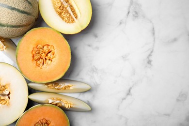 Photo of Tasty colorful ripe melons on white marble table, flat lay. Space for text