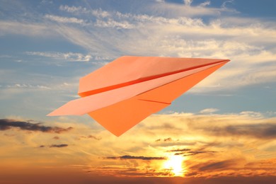 Image of Orange paper plane and view of beautiful sky at sunset