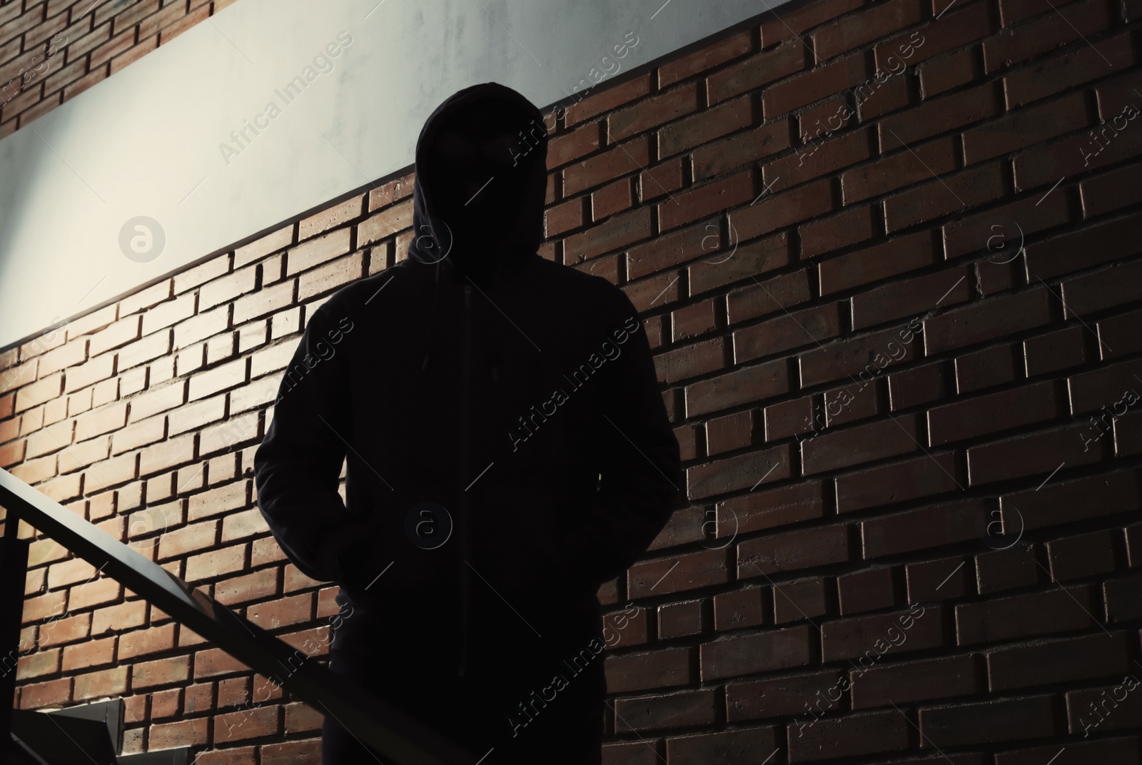 Photo of Silhouette of mysterious man in hoodie indoors. Dangerous criminal