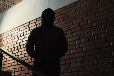 Photo of Silhouette of mysterious man in hoodie indoors. Dangerous criminal