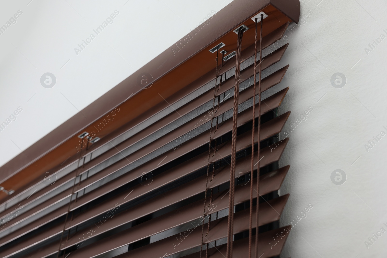 Photo of Stylish horizontal window blinds on white wall, closeup