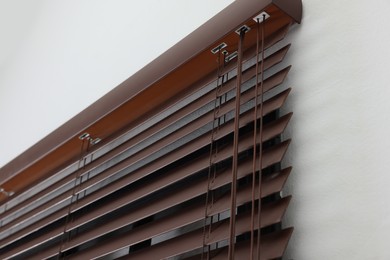 Photo of Stylish horizontal window blinds on white wall, closeup