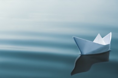 Photo of White paper boat floating on river, space for text