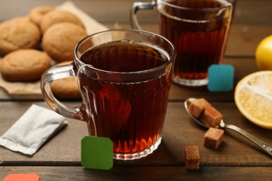 Photo of Tea bags in glass cups of hot water and sugar cubes 
on wooden table