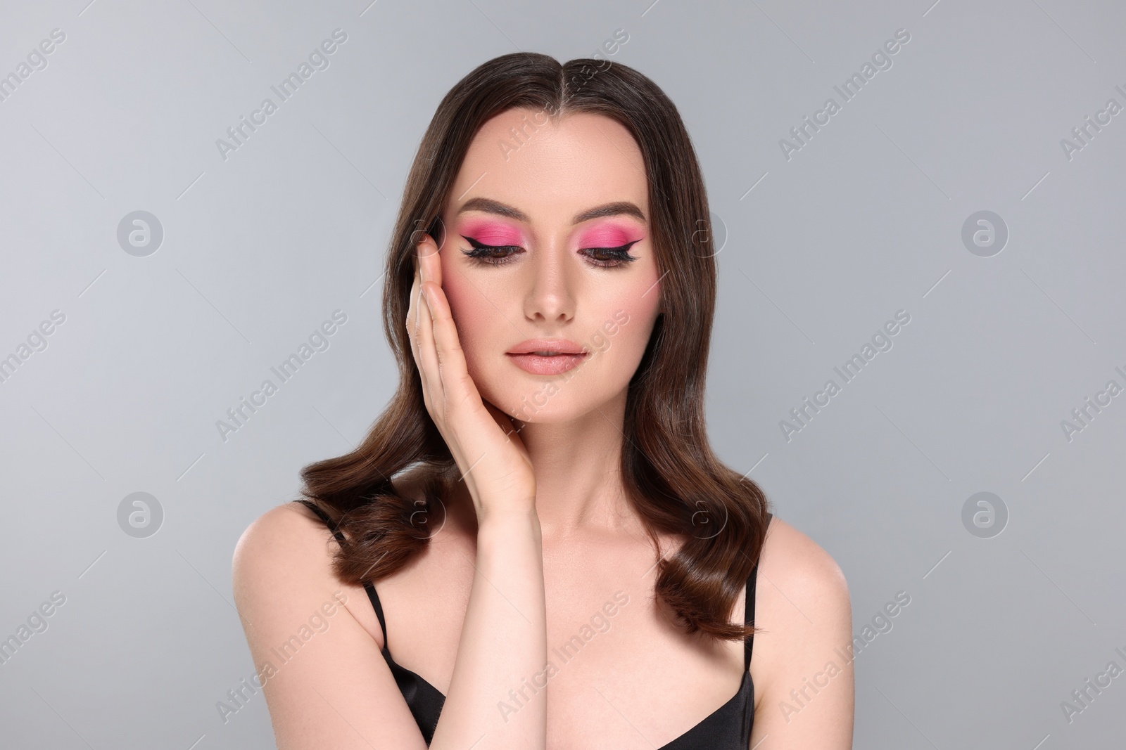 Photo of Portrait of beautiful young woman with makeup and gorgeous hair styling on light grey background