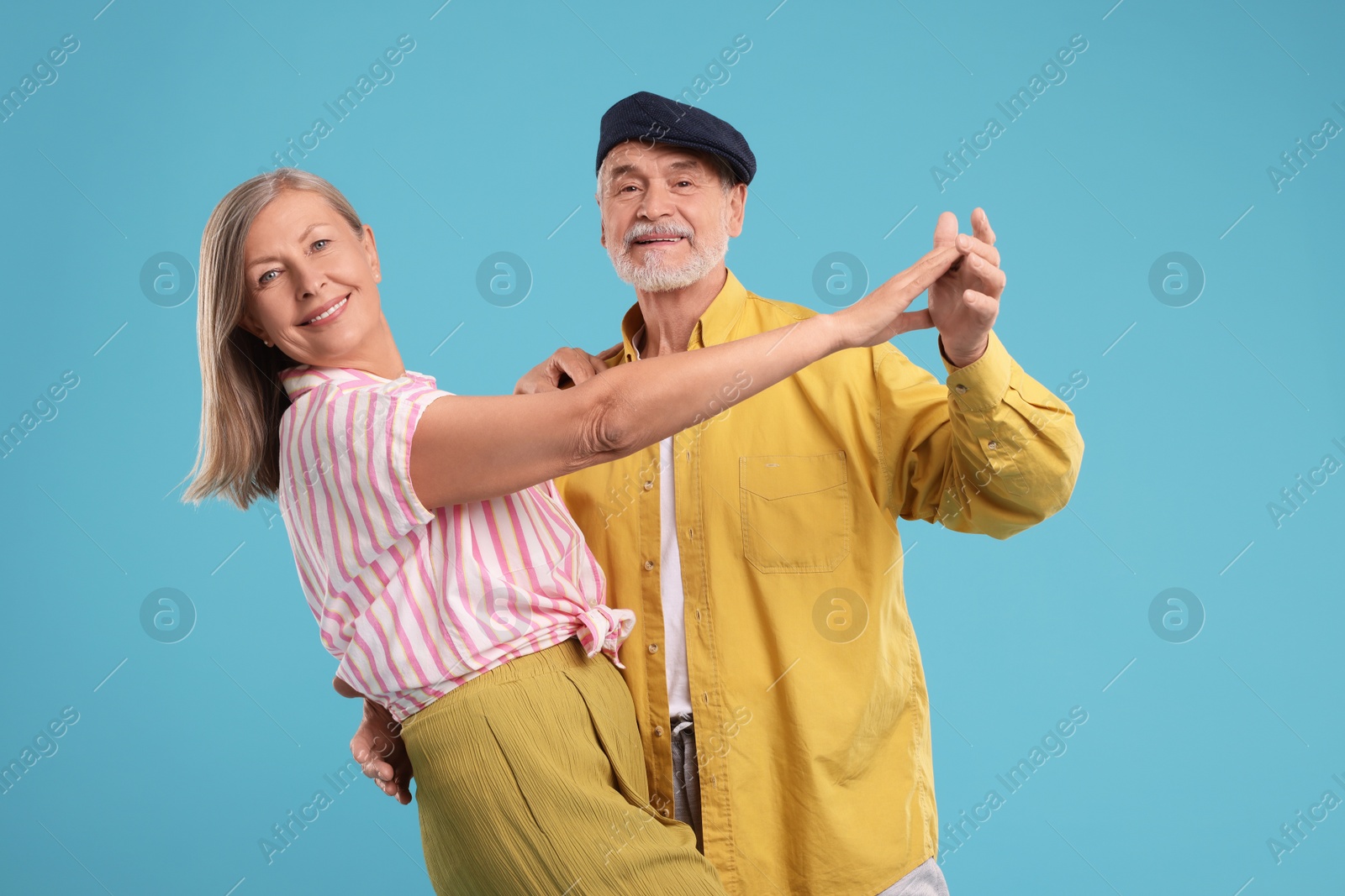 Photo of Senior couple dancing together on light blue background