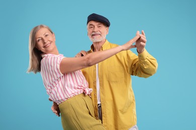 Senior couple dancing together on light blue background