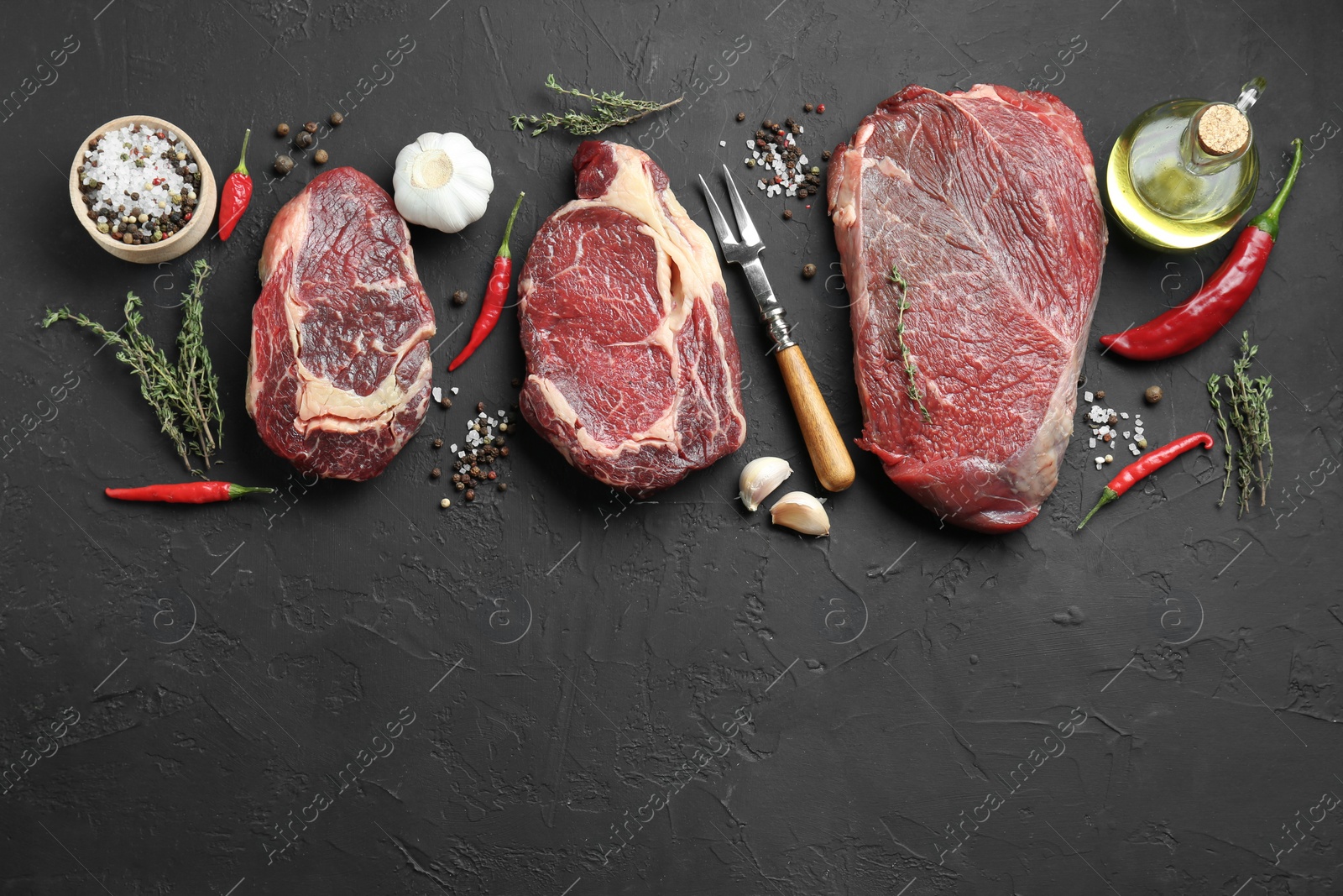 Photo of Pieces of raw beef meat, products and spices on black textured table, flat lay. Space for text