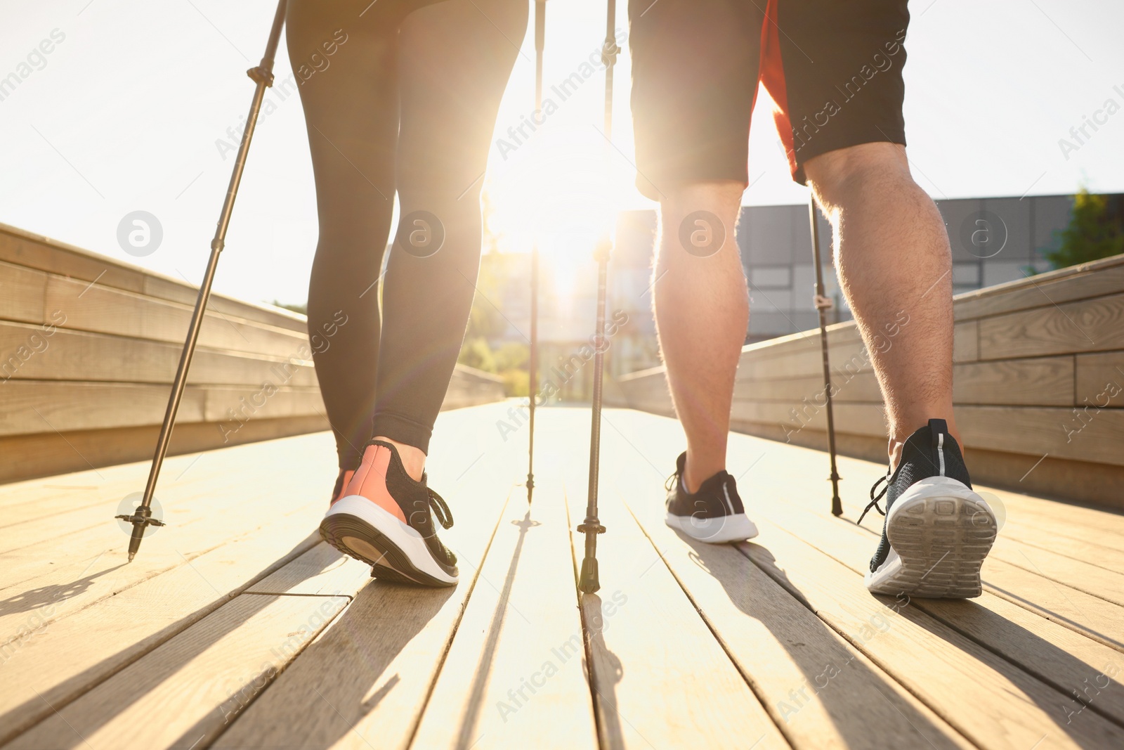 Photo of Couple practicing Nordic walking with poles outdoors on sunny day, closeup