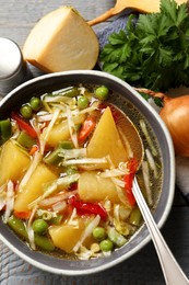 Bowl of delicious turnip soup served on grey wooden table, flat lay