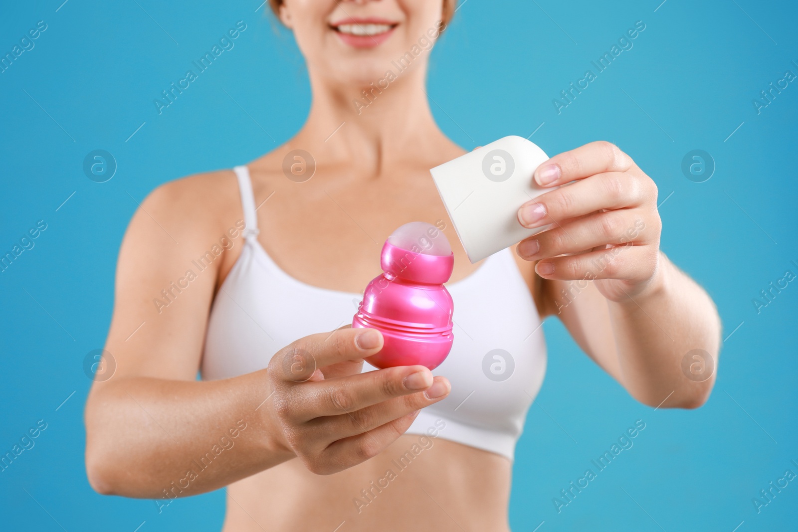 Photo of Young woman holding deodorant on teal background, closeup