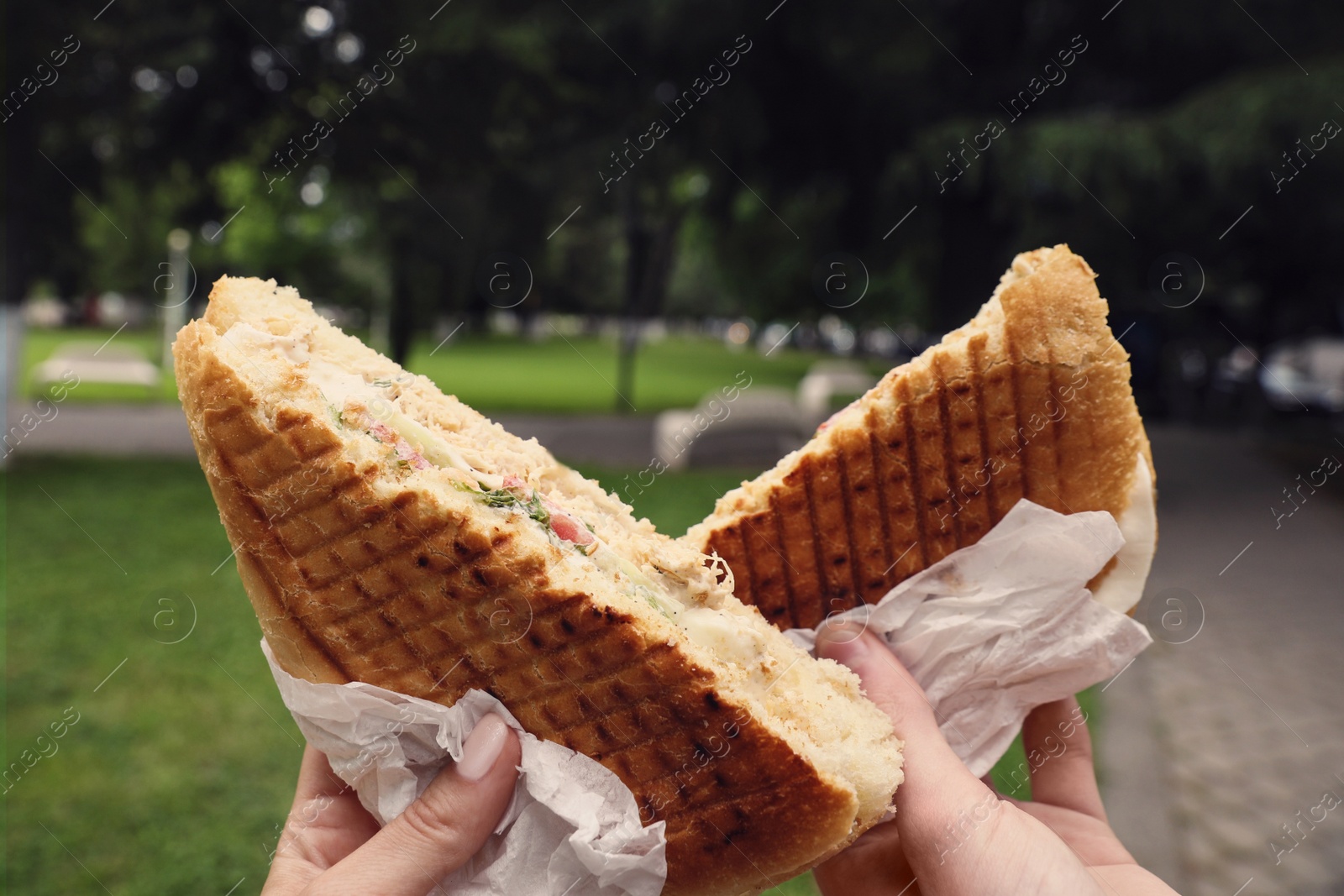 Photo of Man and woman holding delicious sandwiches outdoors, closeup. Street food