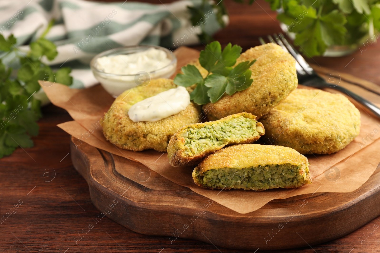 Photo of Tasty vegan cutlets served with sauce and parsley on wooden table, closeup