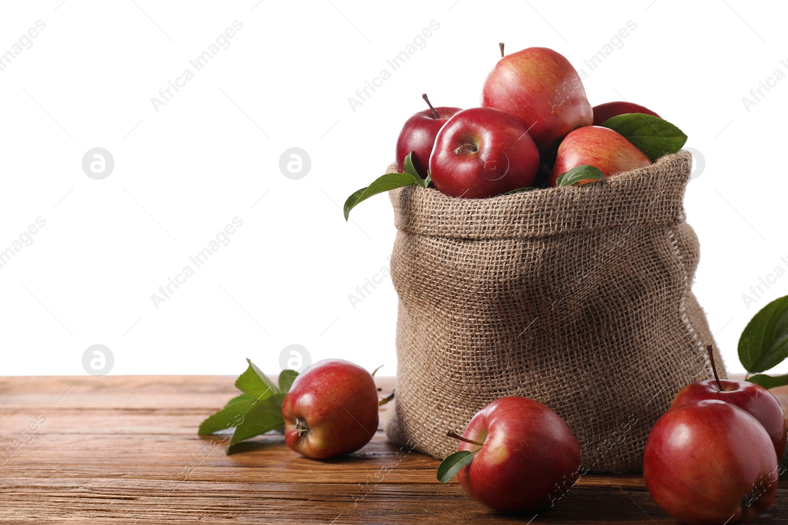 Photo of Ripe red apples with leaves in sack on wooden table against white background. Space for text