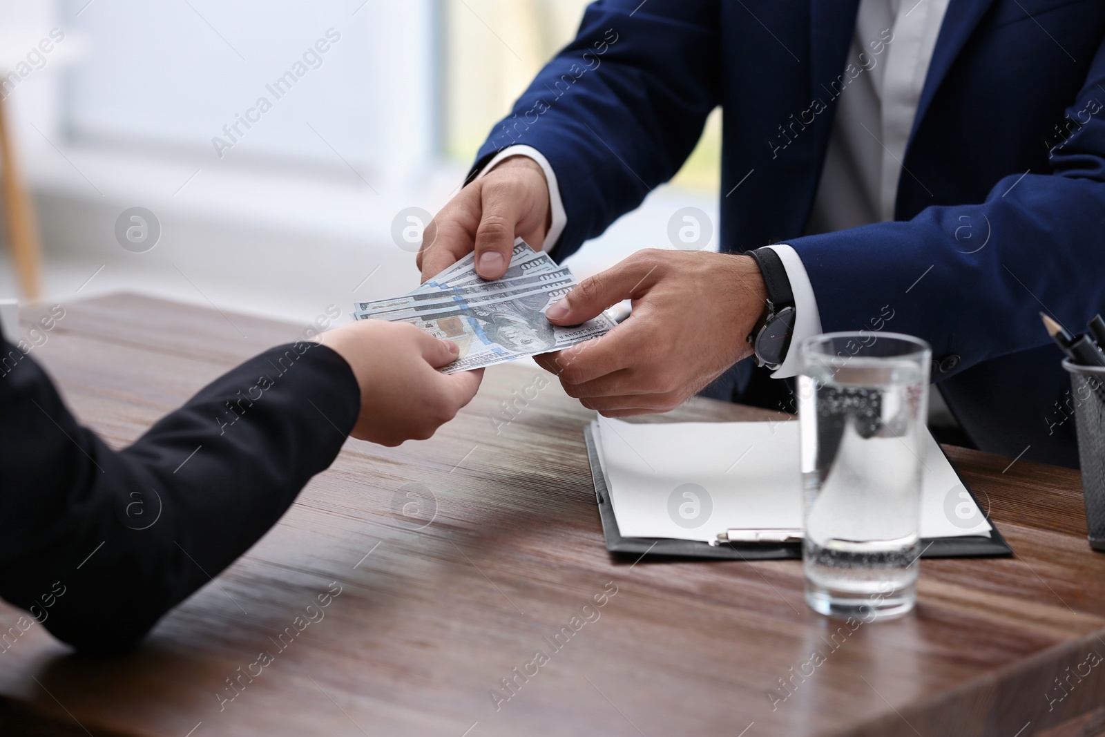 Photo of Woman giving bribe money to man at table, closeup