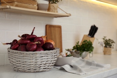 Photo of Fresh onions on white countertop in modern kitchen