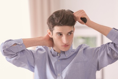 Photo of Portrait of young man combing his hair indoors