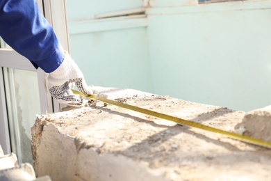 Photo of Worker taking measurement for window installation indoors, closeup