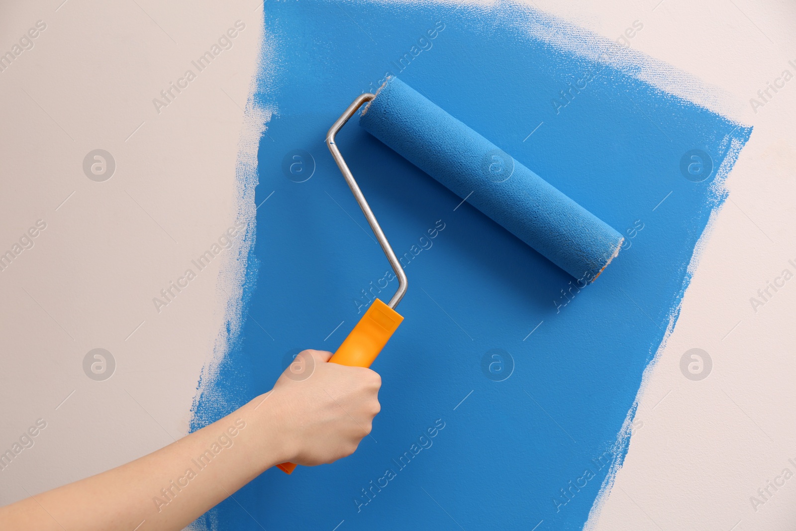 Photo of Woman painting wall with roller, closeup. Redecoration