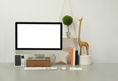 Photo of Modern workplace with computer, charging devices and decor elements. Interior design