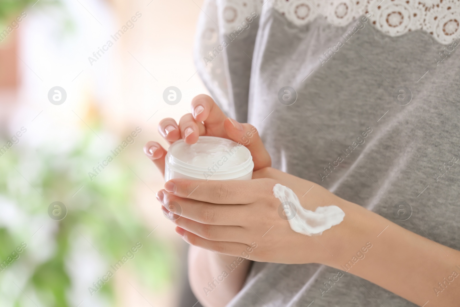 Photo of Young woman with jar of hand cream, closeup