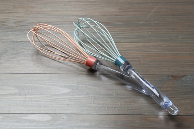 Photo of Two whisks on wooden table. Kitchen tool