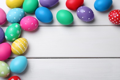 Photo of Colorful eggs on white wooden background, flat lay with space for text. Happy Easter