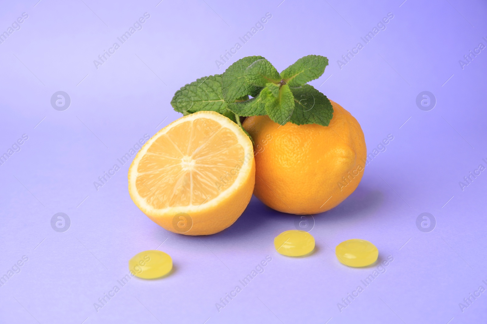 Photo of Fresh lemons, mint leaves and cough drops on lilac background