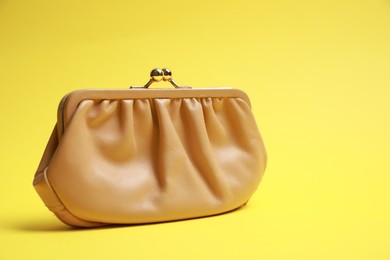 Stylish beige leather purse on yellow background. Space for text