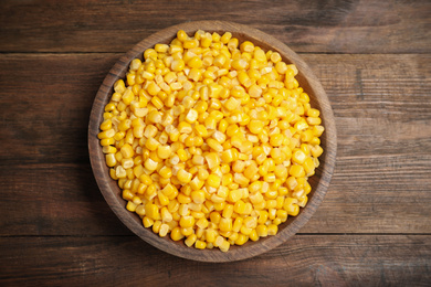 Delicious canned corn in bowl on wooden table, top view