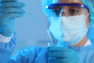 Scientist dripping sample into test tube on blurred background, closeup. Medical research