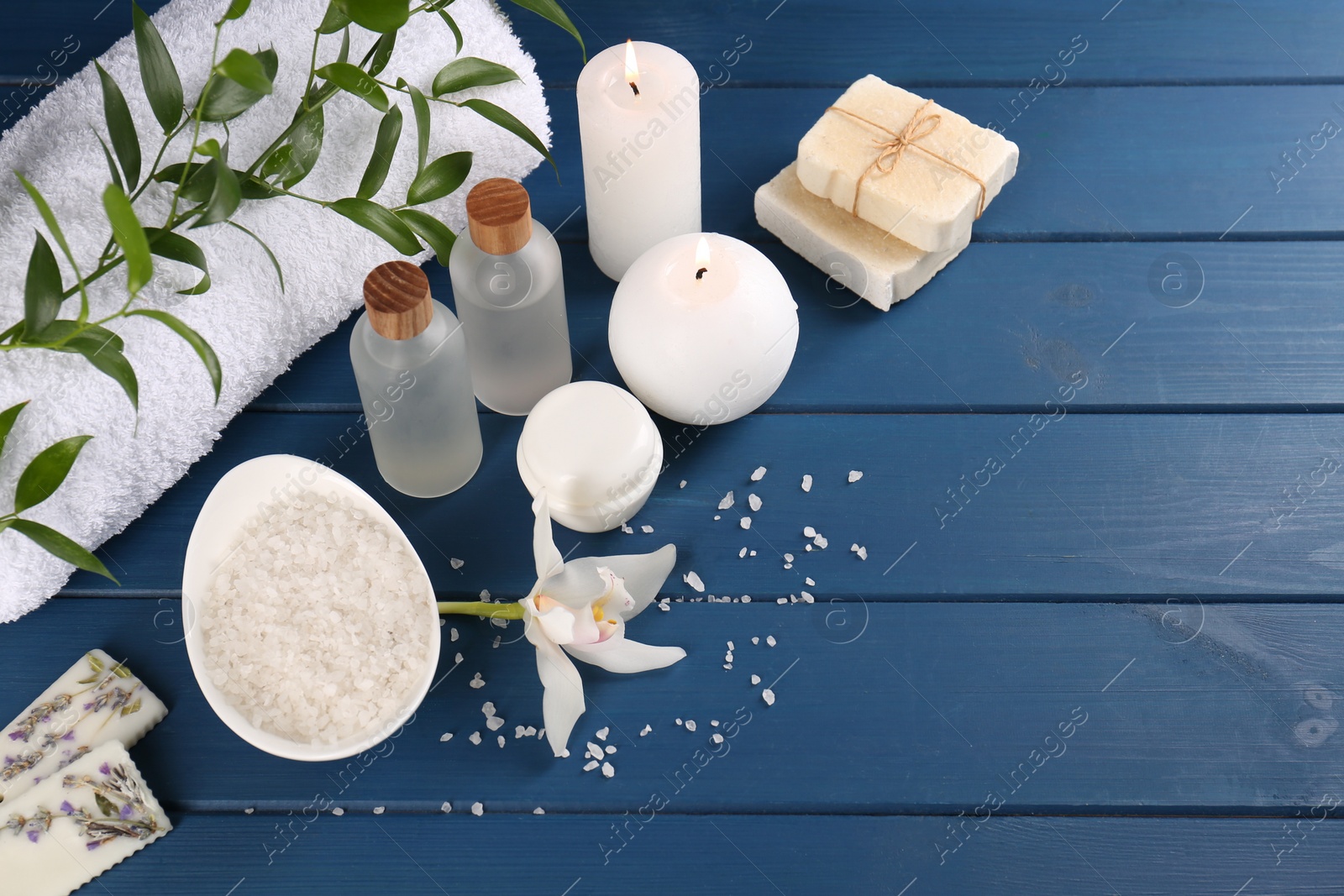 Photo of Beautiful composition with different spa products and candles on blue wooden table, above view with space for text. Retreat concept